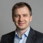 Портрет уверенного российского бизнесмена с дружелюбным взглядом на размытом нейтральном фоне в студии