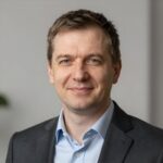 Портрет уверенного российского бизнесмена с дружелюбным взглядом на размытом нейтральном фоне в студии